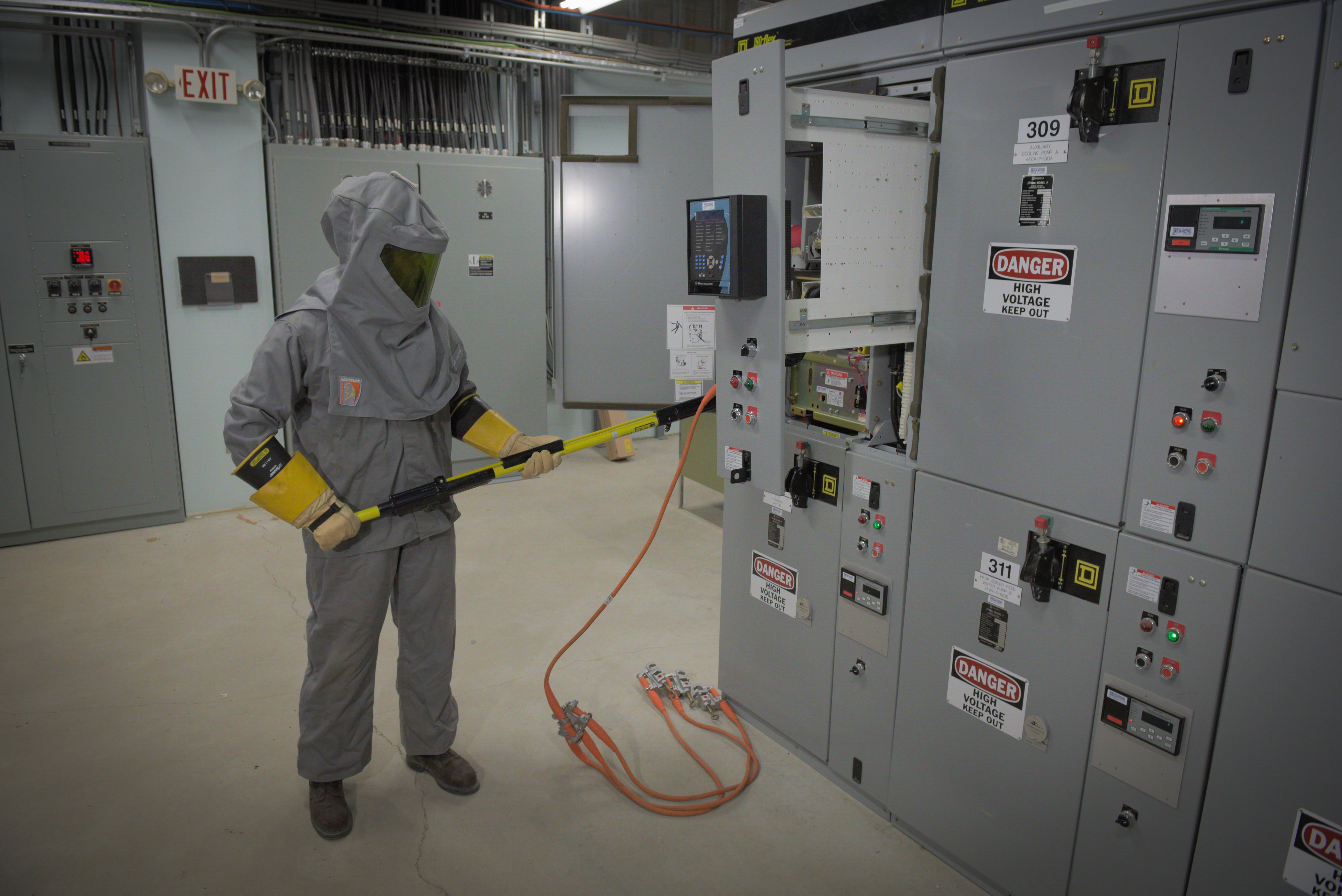  Dynamo employee using High voltage hot stick to minimize risk to person and equipment. The employee is in full protective arc flash suit.